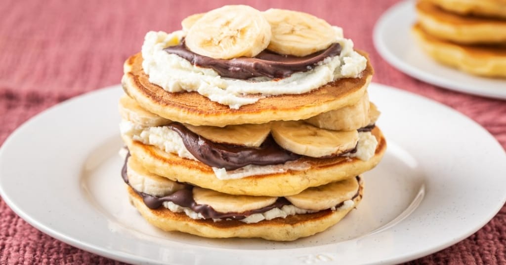 Piastra con gustosi pancake alla banana sul primo piano del tavolo della  cucina